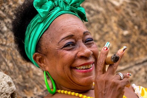 Old Cuban woman with green hair bow smokes a Havana cigar, Cuban woman with cigar and lacquered