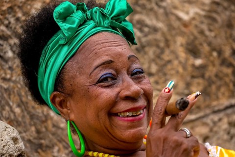 Old Cuban woman with green hair bow smokes a Havana cigar, Cuban woman with cigar and lacquered