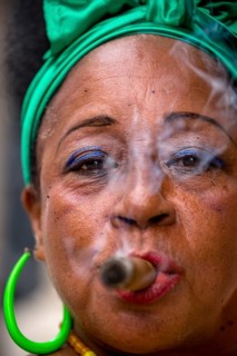 Old Cuban woman with green hair bow smokes a Havana cigar, Cuban woman with cigar and lacquered