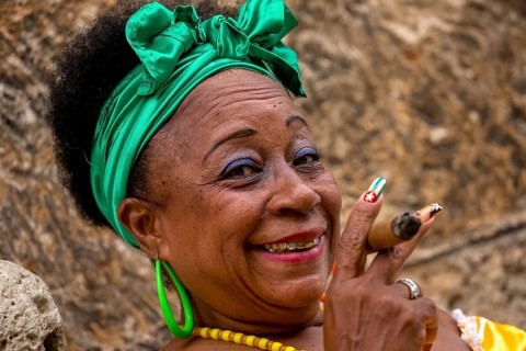 Old Cuban woman with green hair bow smokes a Havana cigar, Cuban woman with cigar and lacquered