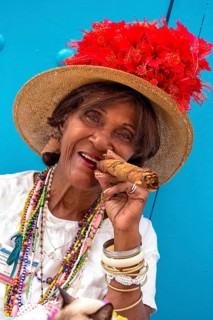Old Cuban woman smokes a Cuban cigar on the street and posts with her cat for the tourists, La