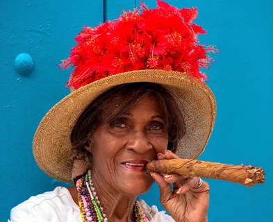 Old Cuban woman smokes a Cuban cigar on the street and posts with her cat for the tourists, La