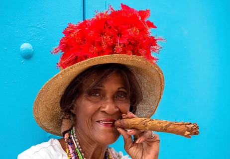 Old Cuban woman smokes a Cuban cigar on the street and posts with her cat for the tourists, La