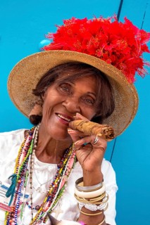 Old Cuban woman smokes a Cuban cigar on the street and posts with her cat for the tourists, La