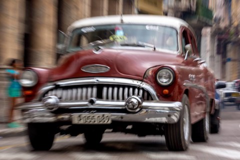 Red vintage car in street scene, Old American road cruiser on the streets of Havana, taxi, La