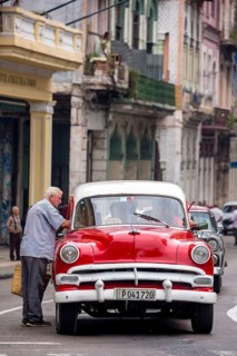 Red and white vintage car in street scene, Old American street cruiser on the streets of Havana,