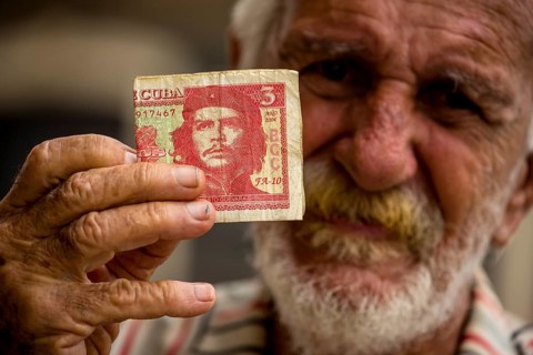Old Cuban man holding a three peso banknote with the portrait of Ernesto Che Guevara in his hand,