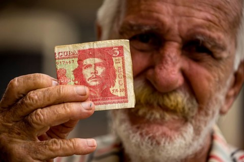 Old Cuban man holding a three peso banknote with the portrait of Ernesto Che Guevara in his hand,