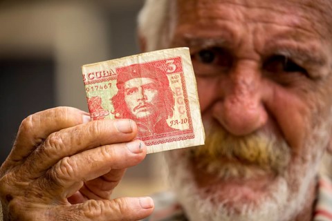 Old Cuban man holding a three peso banknote with the portrait of Ernesto Che Guevara in his hand,