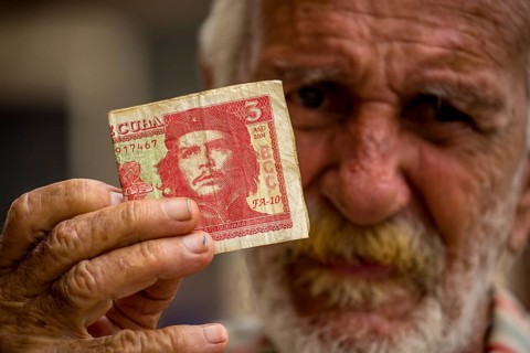 Old Cuban man holding a three peso banknote with the portrait of Ernesto Che Guevara in his hand,