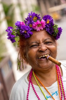 Old Cuban woman with flowers and cigar posing for a tip for tourists, La Habana, Havana, Cuba,