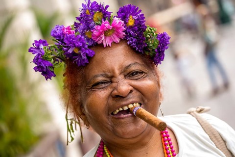 Old Cuban woman with flowers and cigar posing for a tip for tourists, La Habana, Havana, Cuba,