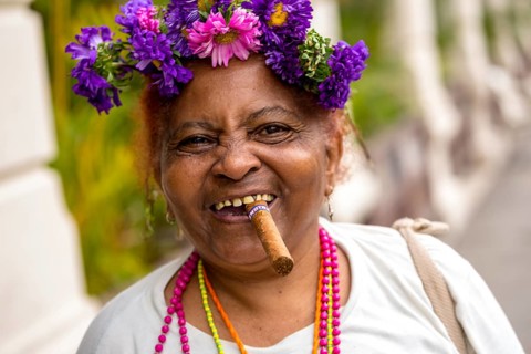 Old Cuban woman with flowers and cigar posing for a tip for tourists, La Habana, Havana, Cuba,