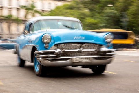 Speed, blurred, moving old car, blue oldtimer in street scene, old american street cruiser on the