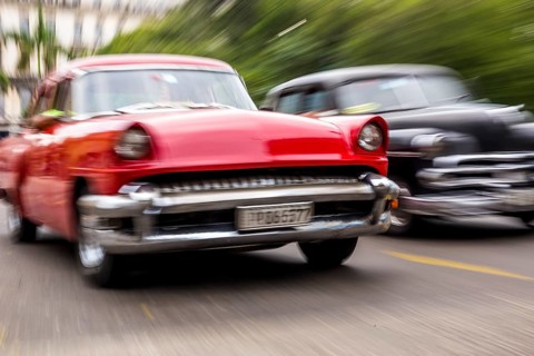 Speed, blurred, moving old car, red oldtimer in street scene, old american street cruiser on the