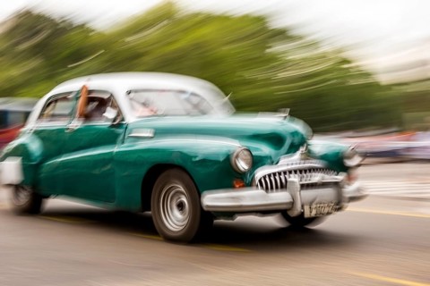 Speed, blurred, moving old car, green oldtimer in street scene, old american street cruiser on the