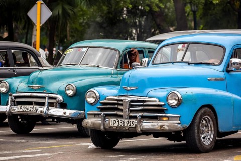 Turquoise and blue vintage car in street scene, Old American road cruiser on the streets of Havana,