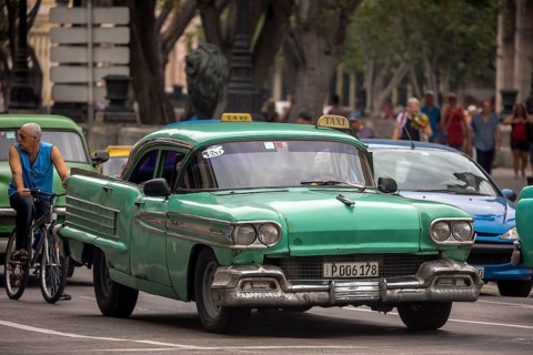 Green vintage car in street scene, Old American street cruiser on the streets of Havana, Taxi, La