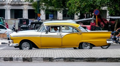 Yellow vintage car in street scene, Old American street cruiser on the streets of Havana, Taxi, La