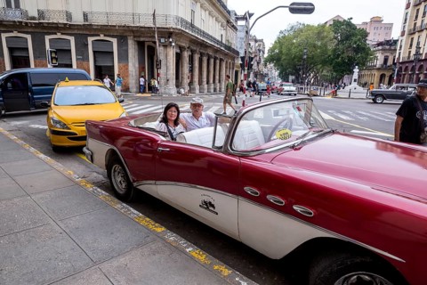 Tourists in a red convertible, red vintage convertible in the street scene, old American street