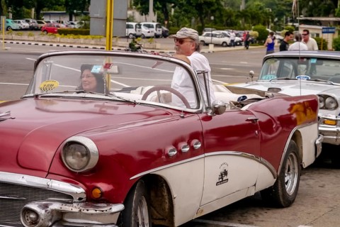 Tourists in a red convertible, red vintage convertible in the street scene, old American road