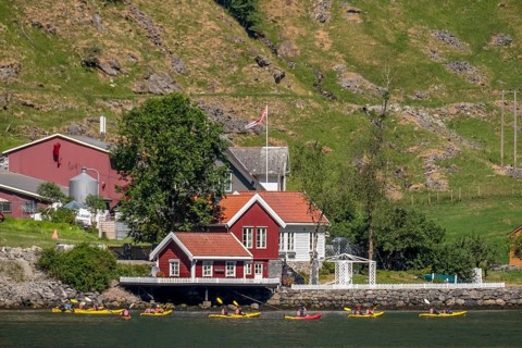 Tourists in yellow kayaks on fjord, river, Gudvangen, stone wall, mountain landscape, red wooden