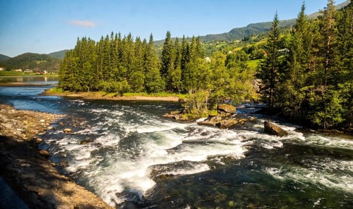 Fjord near the city of Bergen, small island, spruces, rapids, large stones, blue sky, Hordaland,