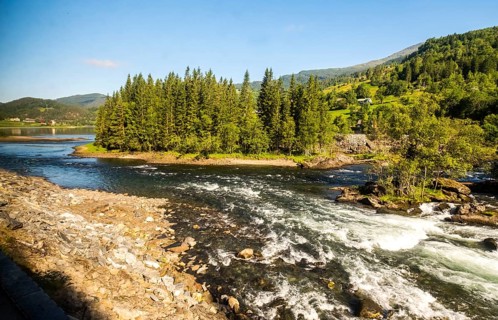 Fjord near the city of Bergen, small island, spruces, rapids, large stones, blue sky, Hordaland,