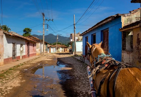 Street scene in Trinidadwith horseback and cobbled street with large puddle of rain, Trinidad,