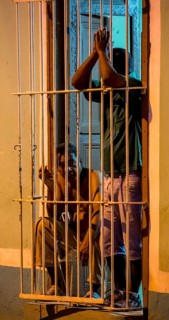Paid car guards behind their barred windows in the old town of Trinidad, Street scene in the old