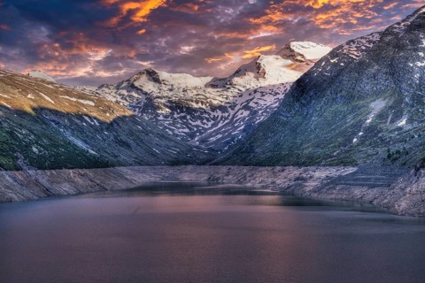 Snowy mountain peaks and a lake at sunset with pink and purple sky, Mattmark reservoir, Saas