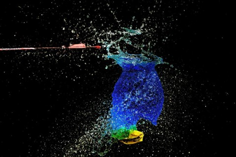 A blue water balloon bursts bubbling, with an arrow and yellow elements in a haunting scene, high