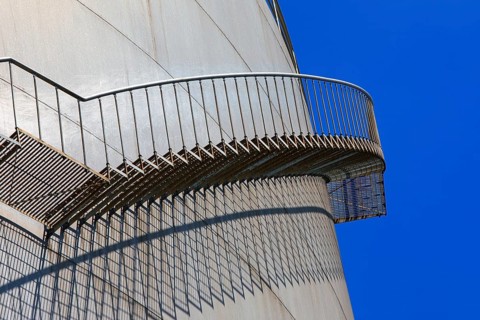 Metal staircase with striking shadow play on the side of a large tank, elevated tank, chemical,