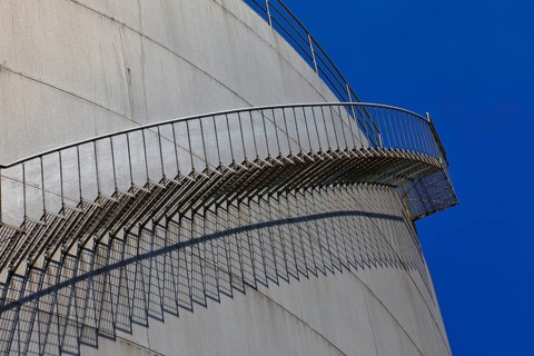 Metal staircase winds around a large tank in an industrial environment, elevated tank, chemical,
