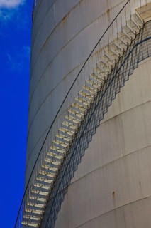 Metal staircase on a large industrial gas tank under a clear blue sky, elevated tank, chemical,