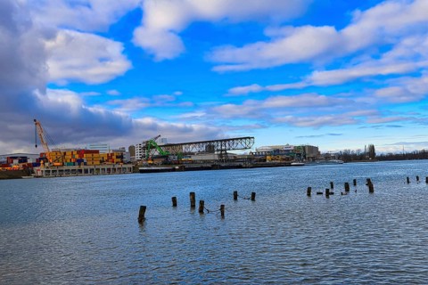 Industrial harbour with containers and cranes under a cloudy blue sky on a river, Rhine, Birsfelden