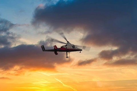 A helicopter flies in front of a dramatic sky with clouds and sunset, transport helicopter, timber
