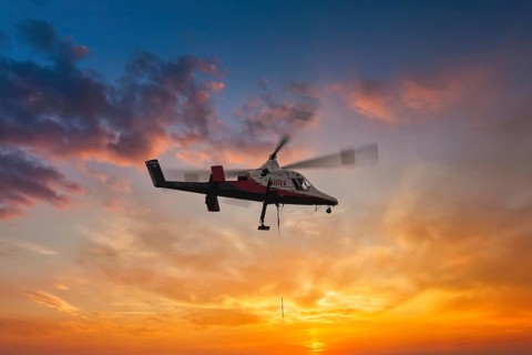 A helicopter hovers elegantly in front of a brightly coloured sunset sky, transport helicopter,