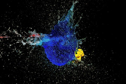 A blue water balloon explosion with yellow accents, triggered by an arrow, in a dynamic scene,