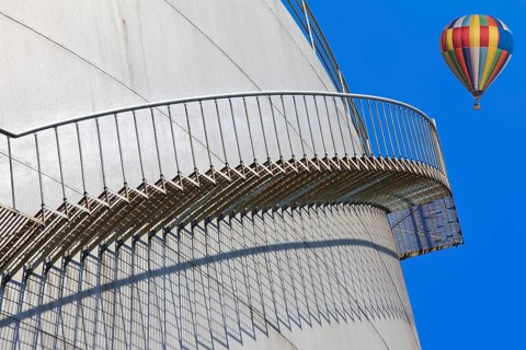 Metal staircase on a tank with a colourful hot air balloon in the sky, elevated tank, chemical,