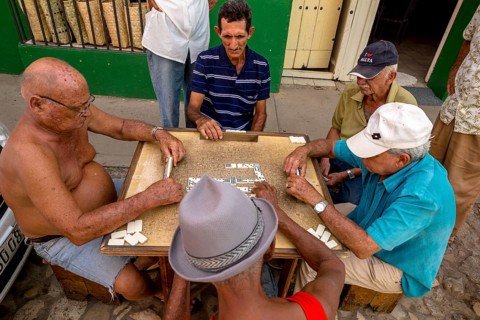 Old Cubans playing dominoes at a table on the street in the city centre of Trinidad, Trinidad,