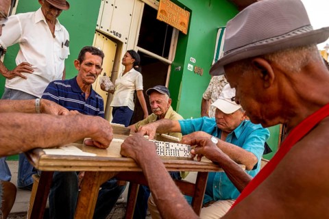 Old Cubans playing dominoes at a table on the street in the city centre of Trinidad, Trinidad,