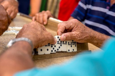 Old Cubans playing dominoes at a table on the street in the city centre of Trinidad, Trinidad,