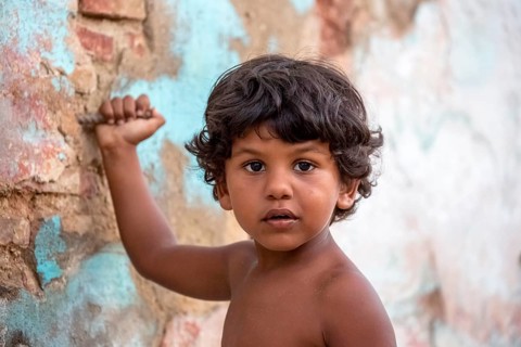 Little Cuban boy on the street in front of an old wall, Street scene in the old town of Trinidad,