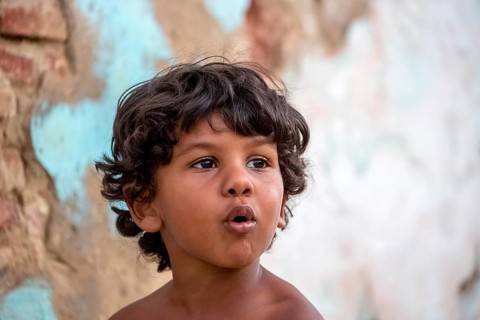 Little Cuban boy on the street in front of an old wall, Street scene in the old town of Trinidad,