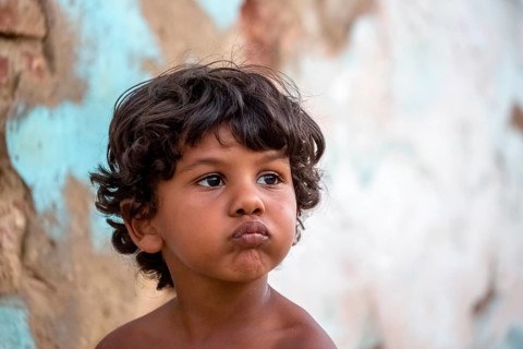 Little Cuban boy on the street in front of an old wall, Street scene in the old town of Trinidad,