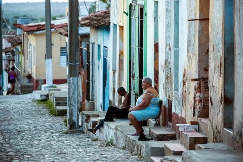 Cubans sitting on their steps in front of their houses in the old town, Street scene in the old