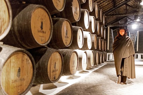 Classic tour guide with student dress, port wine barrels, wine cellar of the Sandemann winery in