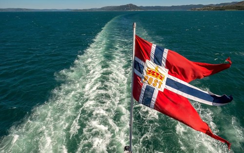 The post symbol on Norwegian flag of a Hurtigruten ship, foaming spray, Trondheimfjord, Agdenes,