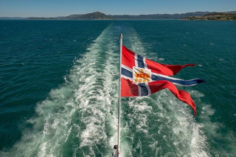 The post symbol on Norwegian flag of a Hurtigruten ship, foaming spray, Trondheimfjord, Agdenes,